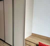 Kompletne zariadený 3-izbový byt s balkónom | PRÚDY Trnava - Izba v 3-izbovom byte s podlahou s dreveným dekorom a úložným priestorom.