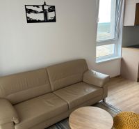 Kompletne zariadený 3-izbový byt s balkónom | PRÚDY Trnava - Obývacia miestnosť s koženou sedačkou, podlahou s dreveným dekorom a oknom.