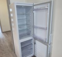 Na prenájom kompletne prerob. NOVÝ 1 izbový byt čiast.zar. Nové Zámky - Otvorená chladnička na podlahe s dreveným dekorom v 1-izbovom byte.