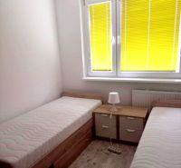 3- izbový byt na ulici Hany Meličkovej  - Spálňa s dvomi posteľami, nočným stolíkom a podlahou s dreveným dekorom v 3-izbovom byte.