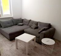 3- izbový byt na ulici Hany Meličkovej  - Sivá sedacia súprava s bielymi stolíkmi na podlahe s dreveným dekorom v 3-izbovom byte.