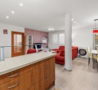 | 3 izbový byt o výmere 73m2 + balkón - Kuchyňa a obývačka v 3-izbovom byte s podlahou s dreveným dekorom a červenou sedačkou.