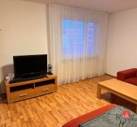 3-izbový byt Prešov, sídl. Sekčov -  REZERVOVANÉ - Obývacia izba 3-izbového bytu s podlahou s dreveným dekorom, TV a červeným sedením.
