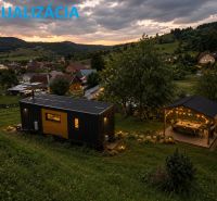 Pozemok na predaj – Horný Vadičov, 1071m2 - Podvečerná krajina s mobilným domom a altánkom na pozemkoch v Hornom Vadičove.