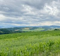 PREDAJ: rekreačný pozemok 564 m2;Bardejov-Zlaté; 39.900 € - Zelené polia a kopce na rekreačných pozemkoch v Bardejove pod zamračenou oblohou.