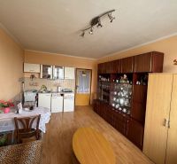 Na predaj Garsônka, 24,5 m2, s perfektnou polohou.  - Garsónka s kuchyňou, obývacou stenou, stolom a podlahou s dreveným dekorom.