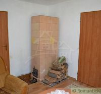Dom so zrekonštruovaným interiérom - Varadka - Izba v rodinnom dome s kachľovou pecou a podlahou s dreveným dekorom.