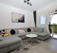 Chorvátsko, Vodice - zariadený apartmán s výhľadom na more - Obývačka v Rekreačnom apartmáne s pohodlnou sivou pohovkou a výhľadom na terasu.