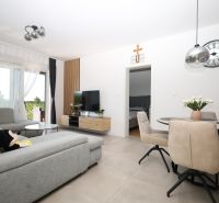Chorvátsko, Vodice - zariadený apartmán s výhľadom na more - Obývačka rekreačného apartmánu so svetlou pohovkou, jedálenským stolom a televízorom.