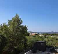 Chorvátsko, Vodice - zariadený apartmán s výhľadom na more - Výhľad z rekreačného apartmánu vo Vodiciach na stromy a Jadranské more.