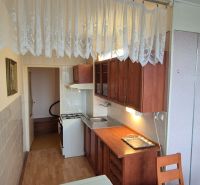 Na predaj 2 izbový byt 62m2 s 3 balkónmi - Nové Zámky  - Kuchyňa v 2-izbovom byte s podlahou s dreveným dekorom a záclonami.