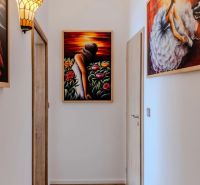 Moderný 2-izbový byt pripravený na okamžité bývanie | Dúbravka - Chodba s obrazmi v 2-izbovom byte, jemný svetelný dizajn a drevené dvere.
