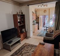 Rodinný dom na predaj Komárno - Obývačka so sedačkou, TV a poličkou, otvorené prepojenie s kuchyňou a jedálenským kútom.