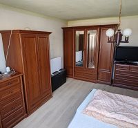 Rodinný dom na predaj Komárno - Spálňa s dreveným nábytkom, podlaha s dreveným dekorom, posteľ, skrine, lampa.