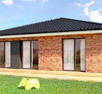 Na predaj 3 stavebné pozemky v centre obce Jasová - Pozemky - bývanie Jasová: Tehlový dom so záhradou a dreveným dekorom na terase.
