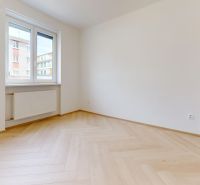 NA PRENÁJOM ZREKONŠTRUOVANÝ 3 IZBOVÝ BYT S GARÁŽOU V CENTRE MESTA - Prázdna izba s podlahou s dreveným dekorom a oknom v 3-izbovom byte.