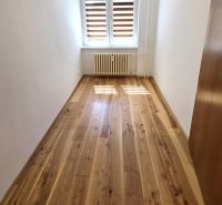 NA PRENÁJOM 4 izbový byt s loggiou, Veľký Šariš - Izba v 4-izbovom byte s veľkým oknom, podlaha s dreveným dekorom.