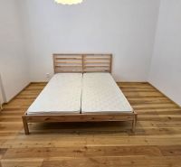 NA PRENÁJOM 4 izbový byt s loggiou, Veľký Šariš - Spálňa v 4-izbovom byte s drevenou posteľou a podlahou s dreveným dekorom.