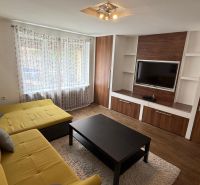 1 izbový 30m2 slnečný byt Zvolen centrum na PRENÁJOM ul. Študentská - Obývacia izba v 1-izbovom byte s veľkou žltou sedačkou, skrinkami a podlahou s dreveným dekorom.