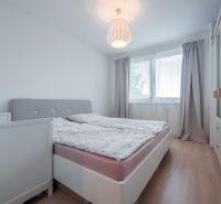 Zariadený- Nízke náklady- Novostavba - Spálňa v 3-izbovom byte s posteľou, skriňou a podlahou s dreveným dekorom.