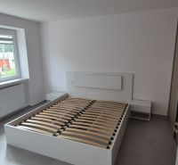 Na prenájom kompletne prerob. NOVÝ 2 izbový byt čiast.zar. Nové Zámky - Svetlá spálňa s posteľou v 2-izbovom byte, podlaha s dreveným dekorom, biele steny.