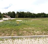Stavebný pozemok v obci Oreské!! - Pozemky - bývanie v Oreskom s trávnatou plochou a betonovou cestou v pozadí.