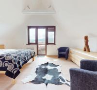 Pripravujeme do ponuky jedinečný apartmánový bytový dom Donovaly  - Svetlá spálňa v chate s dekorom dreva, posteľou a kreslom.