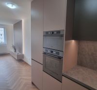 2-izbový moderný byt, s garážovým státím  novostavba, Coboriho ulica - Kuchyňa v 2-izbovom byte s podlahou s dreveným dekorom a zabudovanými spotrebičmi.