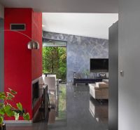 ARCHITEKTÚRA TICHA A MODERNÝCH TECHNOLÓGIÍ - SMART VILLA V OBJATÍ LESA - Interiér rodinného domu s červenou stenou, televízorom a moderným sedením na podlahe s dekorom.