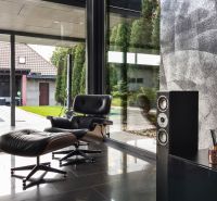 ARCHITEKTÚRA TICHA A MODERNÝCH TECHNOLÓGIÍ - SMART VILLA V OBJATÍ LESA - Kožené kreslo a reproduktor v Rodinnom dome s výhľadom na exteriér.