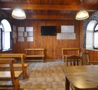 Objekt s historickým nádychom v Banskej Štiavnici - Štefultov - Interiér gastro priestorov s drevenými stenami, lavicami a televízorom na stene.