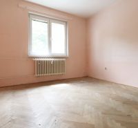Pôvodný stav, neobmedzené možnosti | 3-izbový byt v centre Púchova  - Izba s radiátorom a podlahou s dreveným dekorom v 3-izbovom byte.