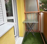 Ponúkame na predaj veľký 2 i byt v Nových Zámkoch, ul. Šafárikova ! - Balkón 2-izbového bytu s posuvnými dverami a skleneným stolíkom, umelý trávnik.
