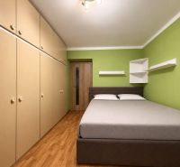 2-izbový byt s vlastnou záhradkou,plynovým kotlom, špajzou  - Spálňa v 2-izbovom byte s posteľou, skriňami a podlahou s dreveným dekorom.