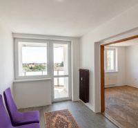 Priestranný 3-izbový byt | 72 m² + 9 m² loggia + 9 m² pivnica |  - Interiér 3-izbového bytu s podlahou s dreveným dekorom, fialovými stoličkami a balkónom.