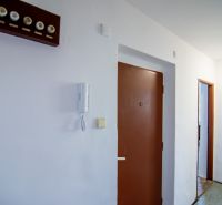 Priestranný 3-izbový byt | 72 m² + 9 m² loggia + 9 m² pivnica |  - Chodba v 3-izbovom byte, biele steny, hnedé dvere, telefón pri vstupe.