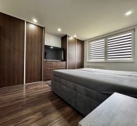 3-izbový byt | 79 m² | Komárno – sídlisko gen. Klapku - Spálňa v 3-izbovom byte s veľkým šatníkom a televízorom, podlaha s dreveným dekorom.