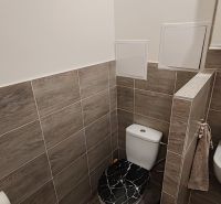 Pekný 1 izbový byt s balkónom na prenájom - Kúpeľňa v 1-izbovom byte s obkladmi, toaletou a podlahou s dreveným dekorom.