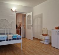 AstonReal: na predaj 2-izbový byt 54 m2 - Poprad, Komenského - Spálňa s bielou posteľou a úložným priestorom, podlaha s dreveným dekorom.