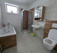 Predaj 4 izbového rodinného domu, pozemok od 523 m2,  NOVOSTAVBA 2023 - Kúpeľňa s vaňou, sprchovacím kútom, zrkadlom a podlahou s dreveným dekorom v rodinnom dome.