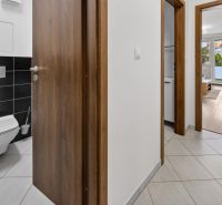 PREDAJ, moderný 2izb byt v novostavbe, Dúbravčická, projekt TuJeToln - Chodba v 3-izbovom byte s výhľadom do obývacej izby, biele steny, podlaha s dekorom.