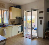 Brač(HR)- zariadený apartmán s výhľadom na more - Kuchyňa v rekreačnom apartmáne s podlahou s dreveným dekorom a prístupom na terasu.