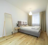 Dizajnový 2-izbový byt s loggiou a parkovaním na prenájom – Miletičova - Spálňa s podlahou s dreveným dekorom, posteľou, zrkadlom a nočným stolíkom v 2-izbovom byte.