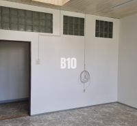 Prenájom obchodných a kancelárskych priestorov - Biela miestnosť v obchodných priestoroch s dlažbou a sklenenými tvárnicami na stene.