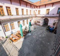 Autentický podnik v Starom Meste - ODSTÚPENIE - Dvor s terasou a stolmi v obchodných priestoroch v Nitre, obklopené historickou architektúrou.