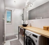 MODERNÝ 3 izbový byt s priestranným balkónom + parking - Kúpeľňa so sprchovacím kútom a práčkou v 3-izbovom byte s dreveným dekorom.