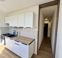 Na prenájom 1-izbový byt s balkónom na Košickej ulici v Humennom - Kuchynská linka s bielymi skrinkami a podlahou s dreveným dekorom v 1-izbovom byte.