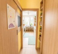 REZERVOVANÉ - Na predaj  4-izbový byt s veľkou lodžiou - Mierová ulica - Úzky interiérový chodba s podlahou s dreveným dekorom vedie do kuchyne so svetlým interiérom.