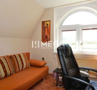 PREDAJ RODINNÉHO DOMU v obci KOŠKOVCE - Pracovňa v rodinnom dome s oranžovou pohovkou, kreslom a výhľadom z okna.