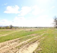 NA PREDAJ: Veľkorysý stavebný pozemok s výhľadom na Vranov - Pozemky - bývanie vo Vranove nad Topľou so zemitou cestou a stromami na horizonte.